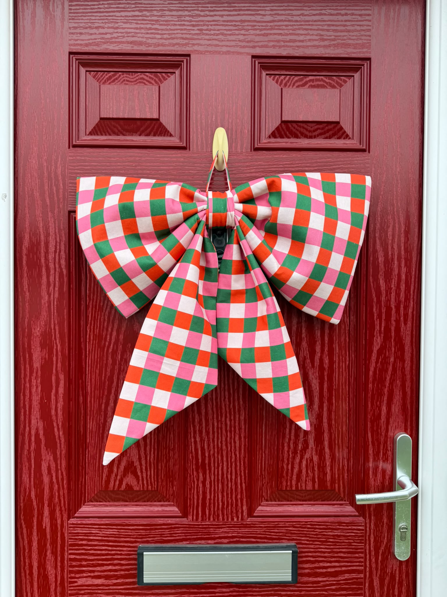 Colourful checked fabric bow hanging on a red door